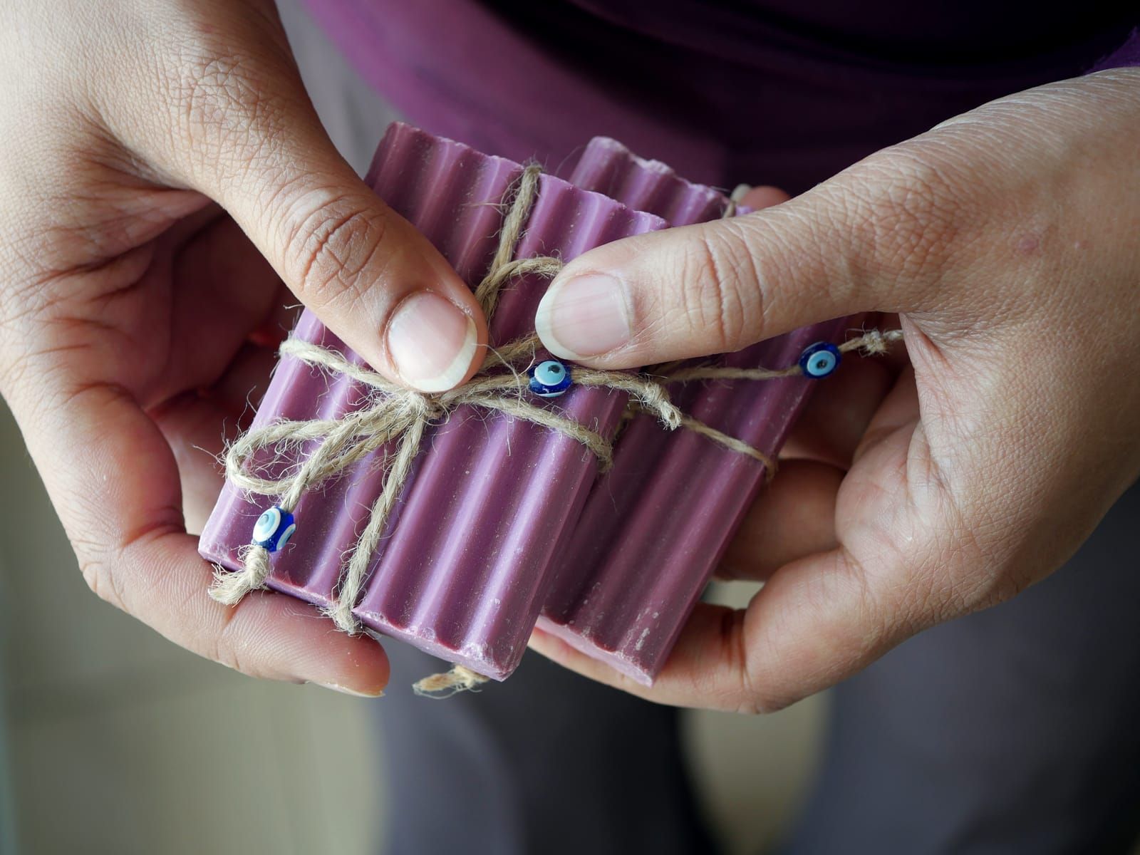 Hands tying twine around handmade soap bars